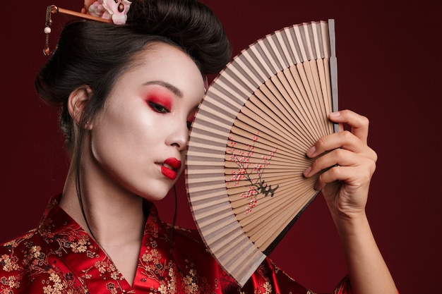 Bild der jungen Geisha-Frau im traditionellen japanischen Kimono, die hölzernen Handfächer hält