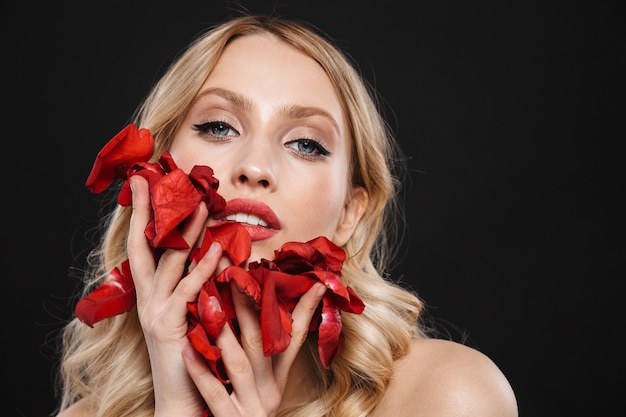 Bild der jungen schönen Frau mit den roten Lippen des hellen Make-ups, die lokalisiert mit Blumenrose aufwerfen.