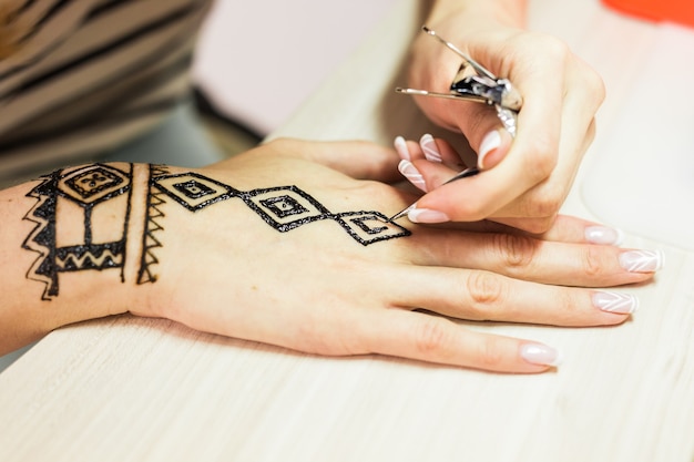 Bild der menschlichen Hand, die mit Henna verziert wird. Mehendi-Hand.