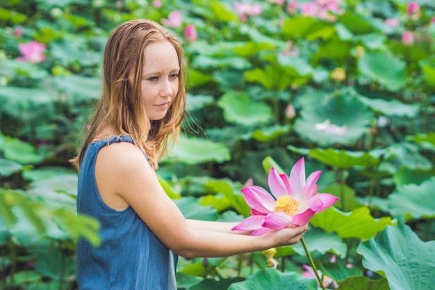 Bild der schönen Frau rothaarig mit Lotusblume in der Hand.