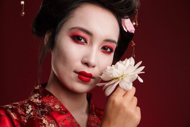 Bild der schönen Geisha-Frau im traditionellen japanischen Kimono mit Blume