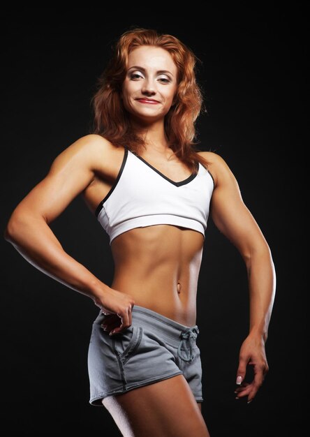 Bild der schönen sportlichen muskulösen Frau lokalisiert auf schwarzem Hintergrund