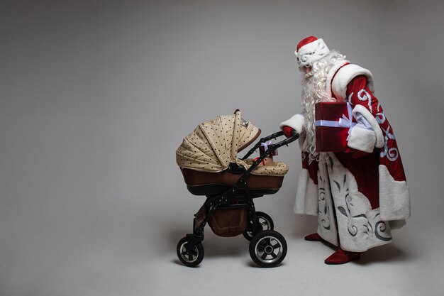 Bild des alten Weihnachtsmanns geht mit einem Babystoller