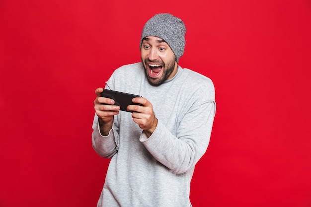Bild des europäischen Mannes 30s, der Smartphone hält und Videospiele spielt, lokalisiert