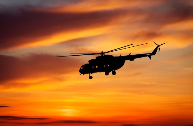 Bild des Hubschraubers bei Sonnenuntergang. Silhouette des Hubschraubers am Sonnenunterganghimmel.