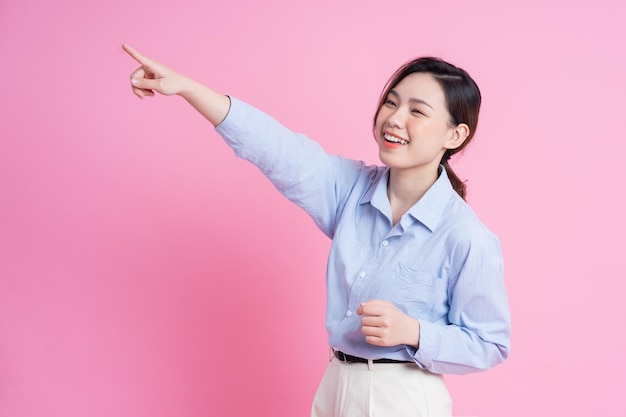 Bild des jungen schönen asiatischen Mädchens, das auf rosa Hintergrund aufwirft