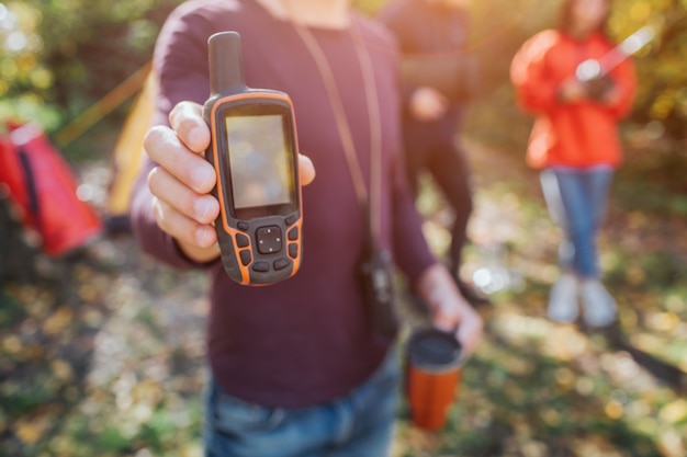 Foto bild des mannes satellitentelefon in der hand halten. junger mann und frau stehen hinter.