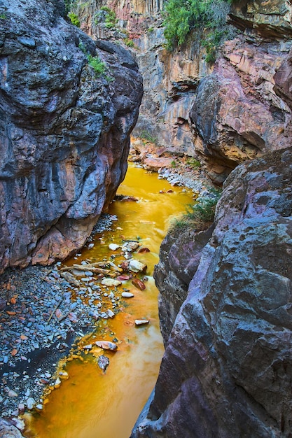 Bild des tiefen Canyons mit großen bunten Felsen und gelbem Flusswasser