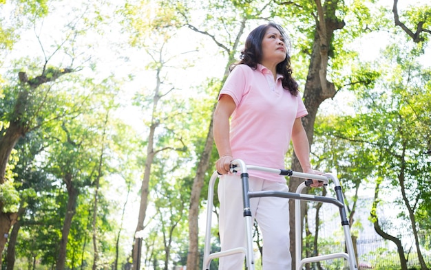 Bild einer asiatischen Frau mittleren Alters, die im Park spazieren geht