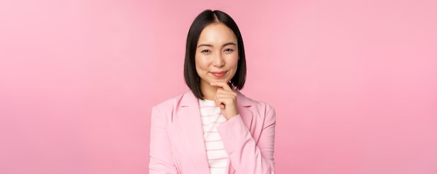 Bild einer asiatischen geschäftsfrau, die in denkender pose brainstoming im anzug steht koreanische verkäuferin unternehmerin posiert vor rosa hintergrund