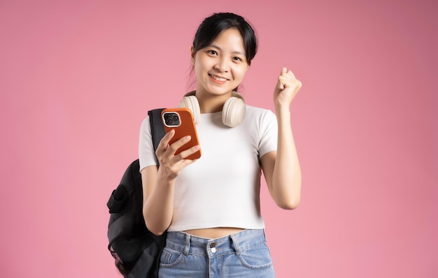 Bild einer asiatischen Studentin mit Telefon und isoliert auf rosa Hintergrund