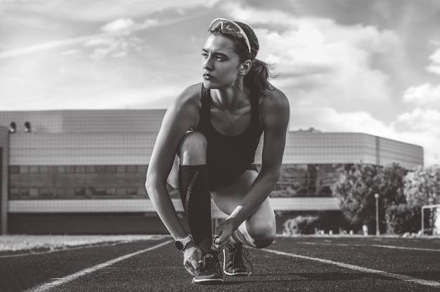 Bild einer Athletin, die ihre Schnürsenkel mit Spikes bindet. Laufendes Konzept.