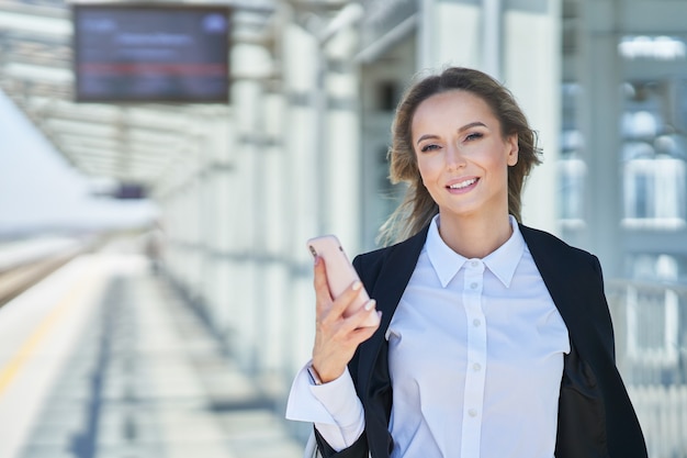 Bild einer eleganten Frau, die mit Tasche und Koffer im Bahnhof spaziert