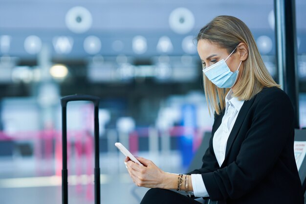 Bild einer erwachsenen Passagierin mit Smartphone am Flughafen