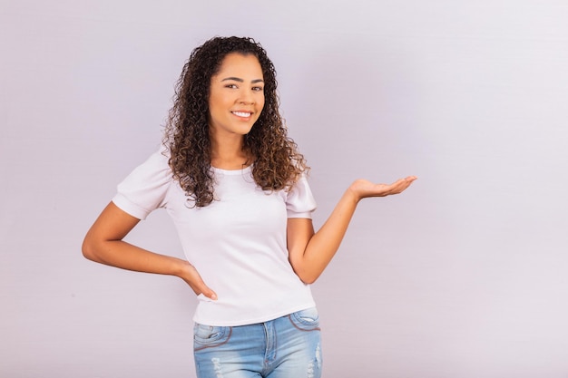 Bild einer fröhlichen jungen Afro-Frau, die auf freien Platz für Text zeigt.