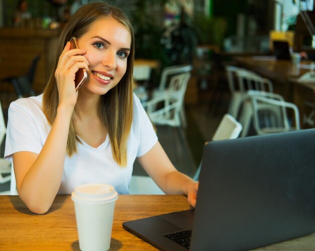 Bild einer glücklichen Frau mit Laptop und Smartphone im Café Lifest