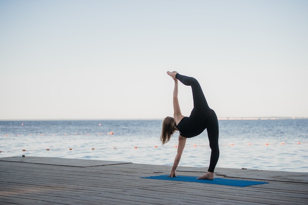 Bild einer hübschen Frau, die Yoga am See tut