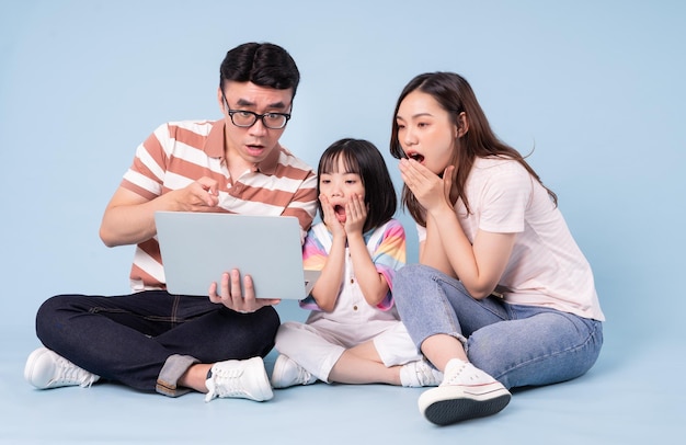 Bild einer jungen asiatischen Familie mit Laptop auf blauem Hintergrund