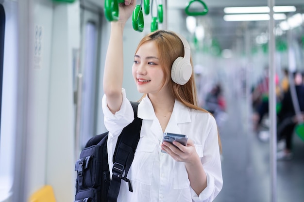 Bild einer jungen asiatischen Frau mit Smartphone in der U-Bahn