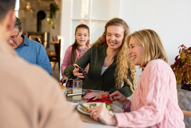 Foto bild einer kaukasischen familie aus mehreren generationen, die beim essen und smartphone-nutzung sitzt. konzept für familie und zeit miteinander verbringen.