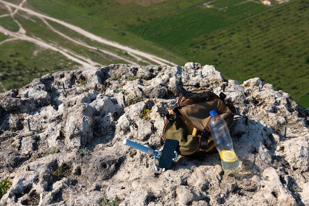 Bild einer Plastikflasche und eines Touristenrucksacks auf einer Bergklippe in freier Wildbahn. Foto in hoher Qualität