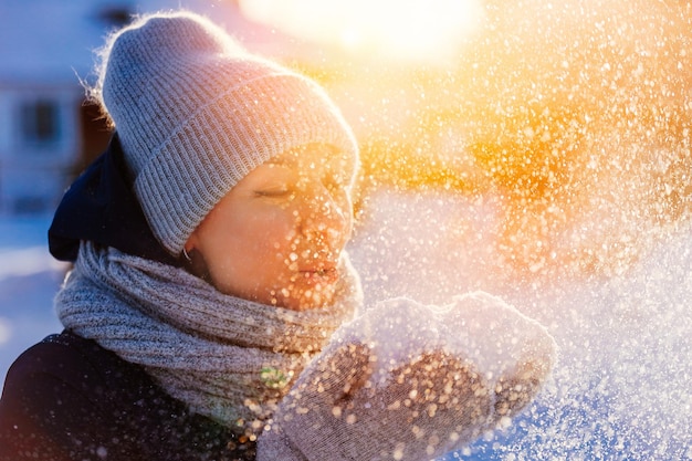 Bild einer schönen Frau in einem gestrickten Wintermützenschal und Fäustlingen Schneetreiben von Palmen an einem Winterabend