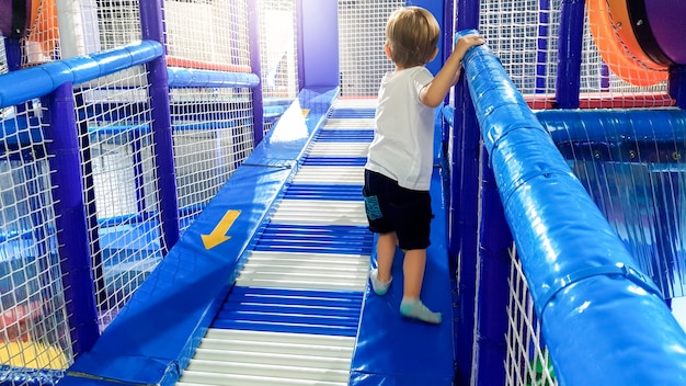 Bild eines 3 Jahre alten Kleinkindjungen, der auf dem Kinderspielplatz im Einkaufszentrum klettert und kriecht. Es gibt viele weiche Matten für die Sicherheit der Kinder