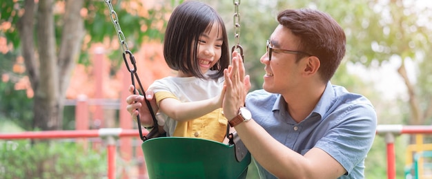 Bild eines asiatischen Vaters und einer Tochter, die zusammen im Park spielen