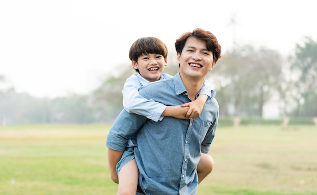 Bild eines asiatischen Vaters und Sohnes, die Spaß im Park haben