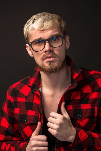 Bild eines attraktiven jungen bärtigen Hipster-Mannes mit Brille im Hemd in einem Käfig auf schwarzem Hintergrund isoliert.