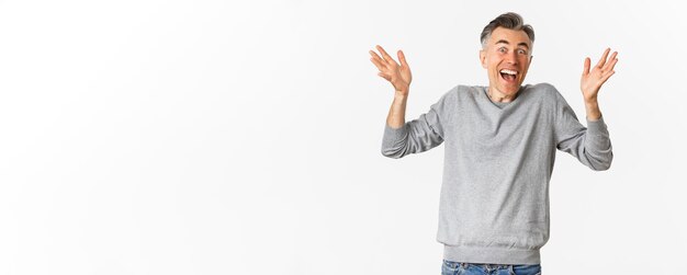 Bild eines aufgeregten und glücklichen Mannes mittleren Alters mit grauer Kurzhaarfrisur, der die Hände hochhebt und st