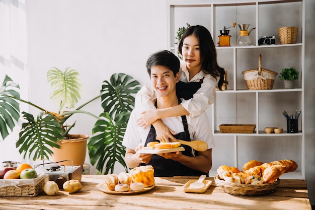 Bild eines frisch verheirateten Paares, das zu Hause kocht Asien junges Paar, das zusammen mit Brot und Obst in der gemütlichen Küche zu Hause kocht