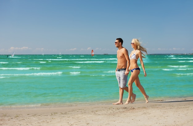 Bild eines glücklichen Paares, das am Strand spazieren geht.