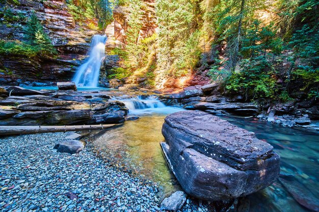 Bild eines großen Felsbrockens im Flussbett am blauen majestätischen Wasserfall in der Schlucht