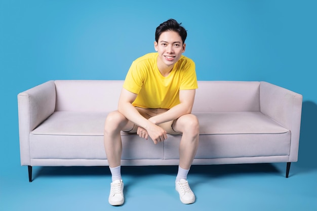 Bild eines jungen asiatischen Mannes, der auf dem Sofa sitzt