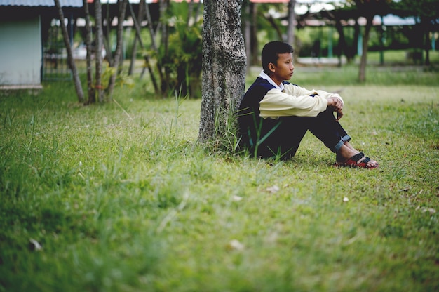 Bild eines Jungen, der traurig alleine im Waldkrisenkonzept sitzt