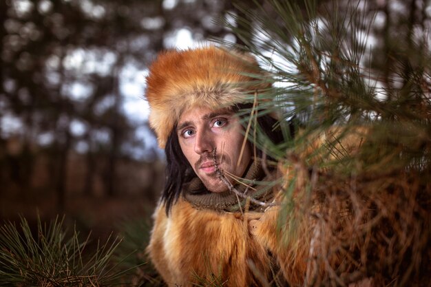 Foto bild eines jungen mannes mit einer fuchspelzmütze im wald