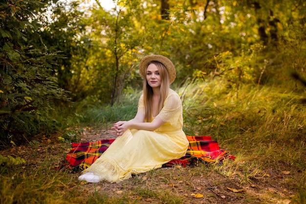 Bild eines Mädchens in einem gelben Kleid, das auf einer Decke im Park sitzt