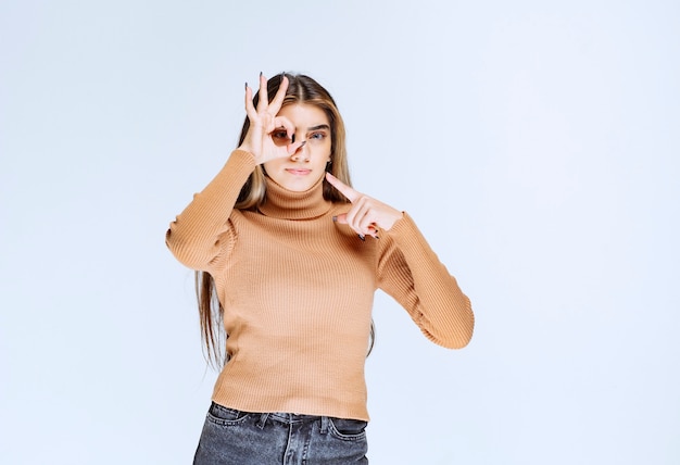 Bild eines Modells der jungen Frau im braunen Pullover, der ok Geste zeigt und zeigt.