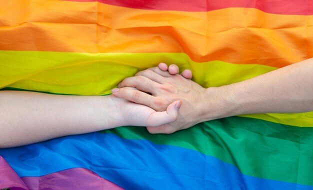 Bild eines schwulen Paares, das sich die Hände an der LGBT-Flagge hält