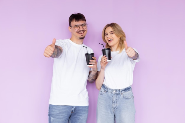 Bild eines zufriedenen Paares von Mann und Frau in Jeanskleidung, das lächelt, während es Kaffeetassen zum Mitnehmen in der Hand hält