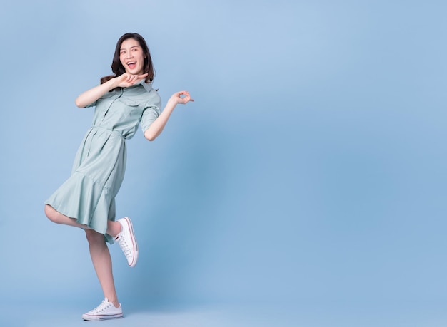 Bild in voller Länge des tragenden Kleides der jungen asiatischen Frau auf blauem Hintergrund