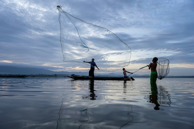 Bild ist Silhouette. Fishermen Casting geht am frühen Morgen mit Holzbooten, alten Laternen und Netzen zum Fischen aus. Lebensstil des Konzept-Fischers