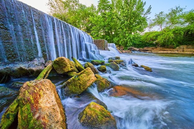 Bild von großen, mit Moos bedeckten Felsbrocken, umgeben von künstlichen Wasserfall und Damm