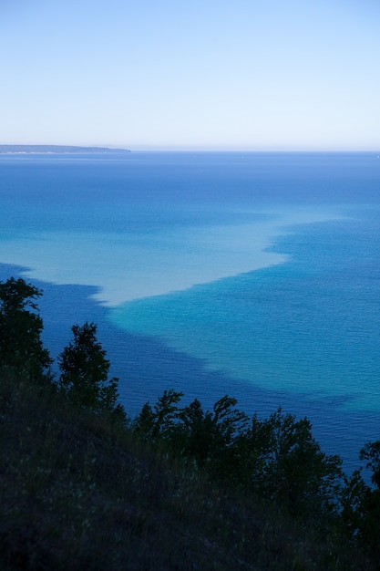 Bild von Hazy Blue View von oben auf Bäume im Vordergrund und Wasser und ein Strand im Hintergrund