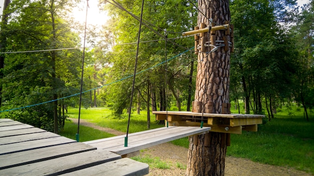 Bild von Holzbrücke und Seilen, die zwischen Bäumen im Park hängen. Extremer Abenteuerpark für Kinder- und Erwachsenenunterhaltung