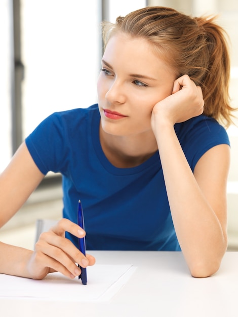 Bild von nachdenklichem Teenager-Mädchen mit Stift und Papier