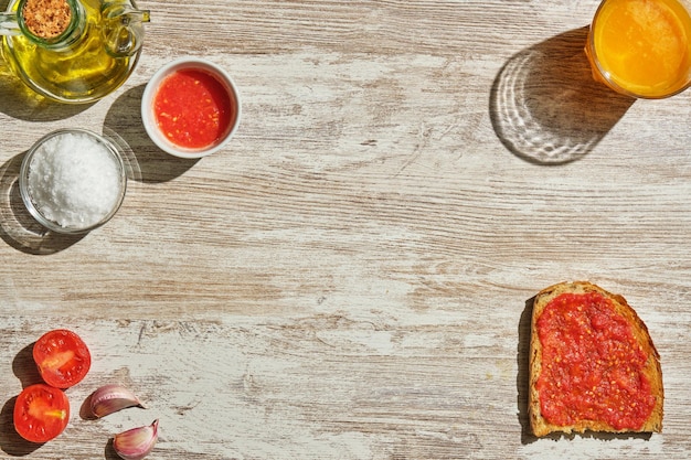 Bild von oben von Toast mit Tomate und ihren Zutaten, die am Rand des Bildes verstreut sind