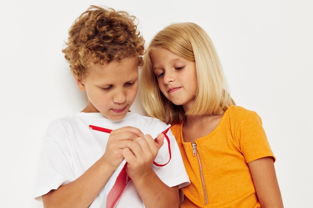 Bild von positivem Jungen- und Mädchenspaß in bunten T-Shirts mit einem Notizblock, isoliertem Hintergrund unverändert