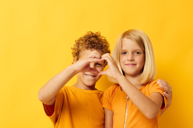 Bild von positiven Jungen und Mädchen, die Mode-Kindheitsunterhaltung auf farbigem Hintergrund kuscheln